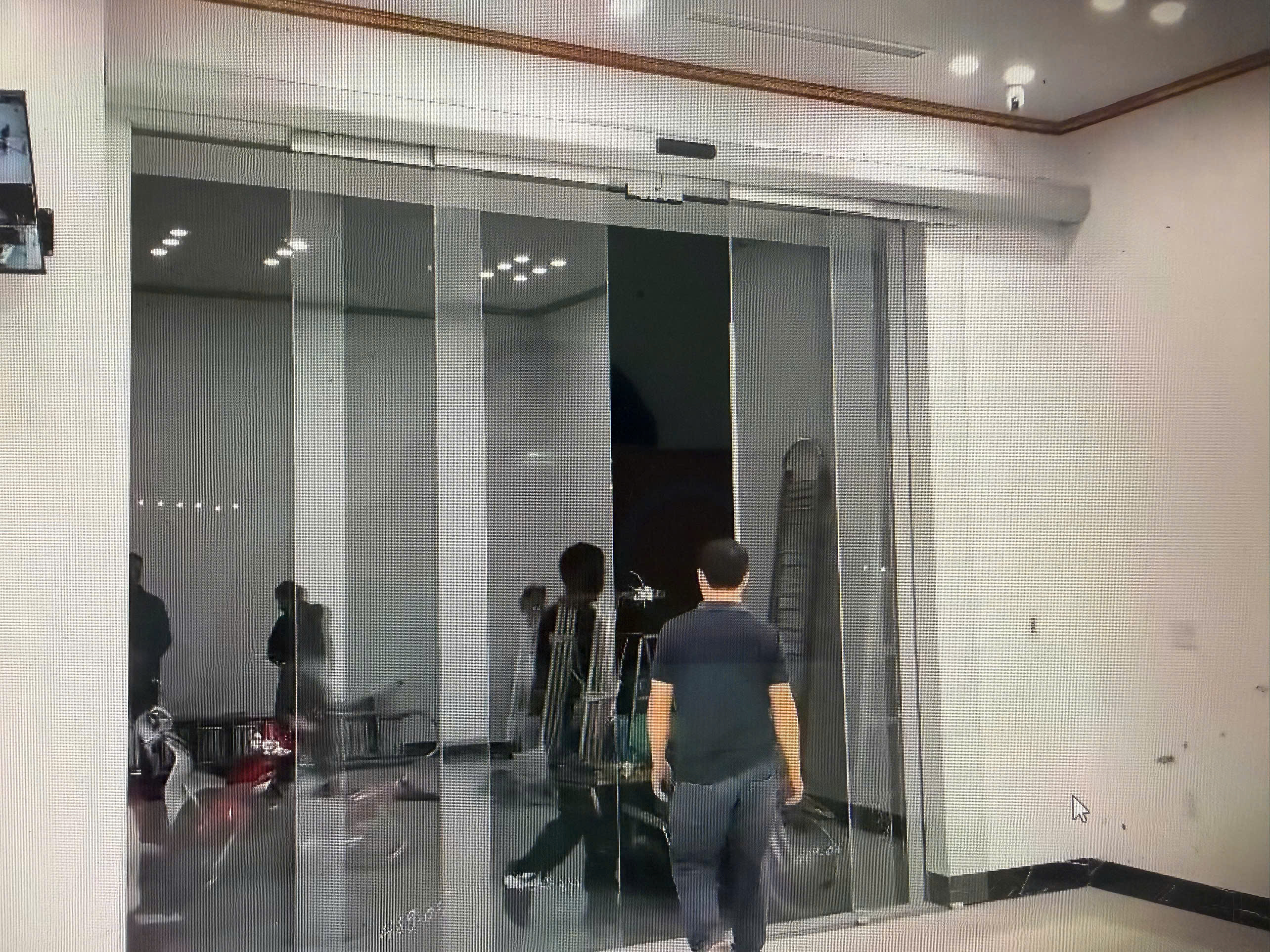 Cửa kính trượt tự động khung nhôm tại sảnh tòa nhà, một người đàn ông đang bước qua cửa